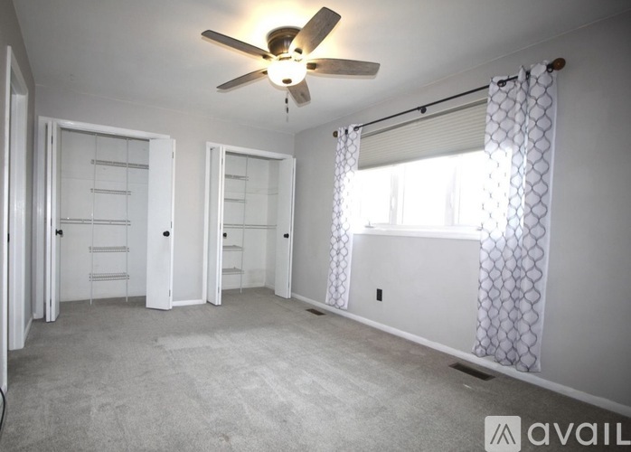 A spacious room with a ceiling fan and two closets.