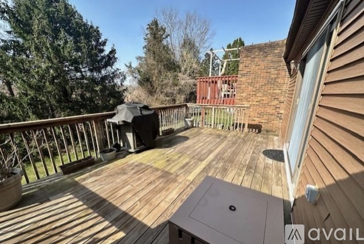 A wooden deck with a table and chairs is surrounded by a wooden fence and trees.