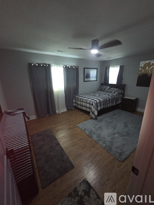 A bedroom with a bed, chair, and a ceiling fan.