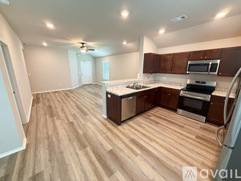 A kitchen with wooden flooring and a refrigerator on the right side.
