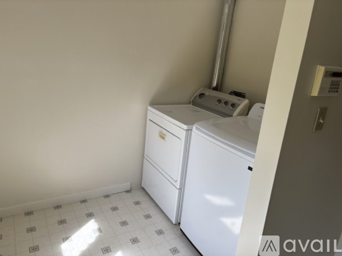 A white dishwasher is in a kitchen with a white tiled floor.