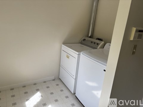 A white dishwasher is in a kitchen with a white tiled floor.