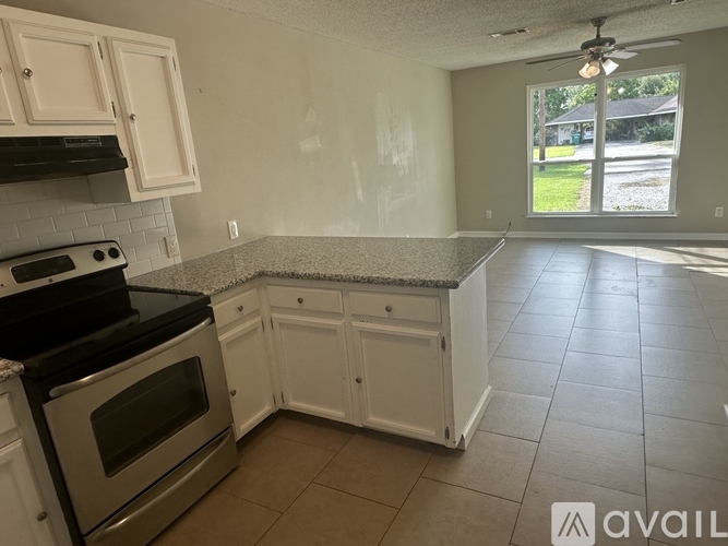 A kitchen with white cabinets and a black stove top oven.