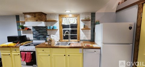 A kitchen with yellow cabinets and a white fridge.