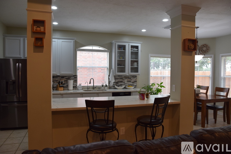 A kitchen with a refrigerator, sink, and a dining table with chairs.