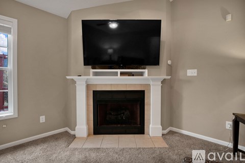 A living room with a fireplace and a television mounted above it.