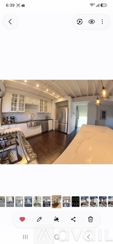 A modern kitchen with white cabinets and a wooden floor.