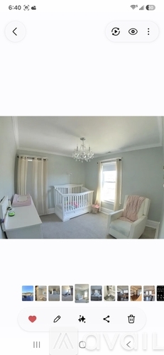 A baby's room with a white crib and a pink chair.