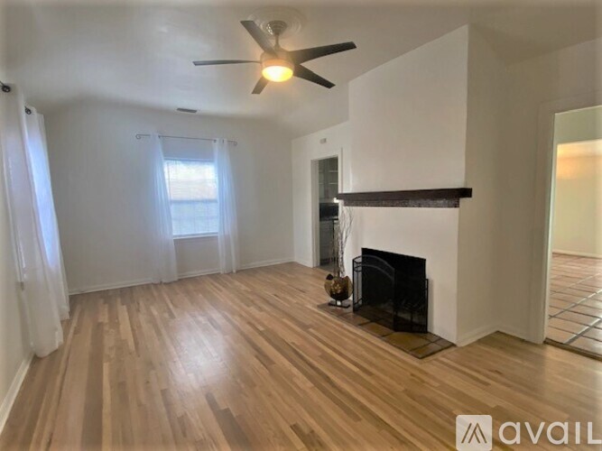 A living room with a fireplace and a ceiling fan.