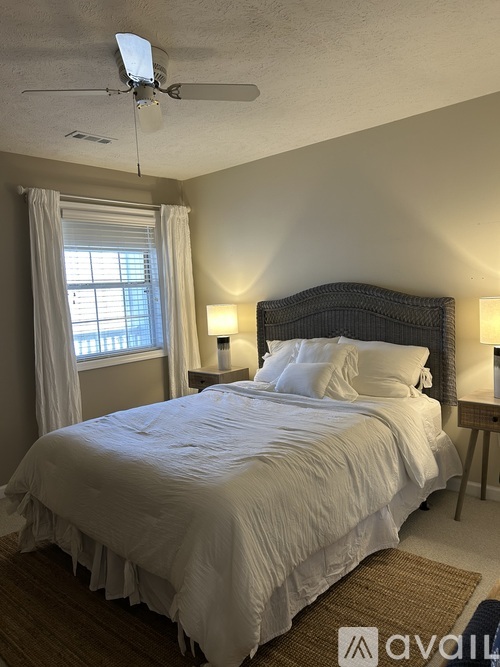 A bedroom with a large bed and a ceiling fan.