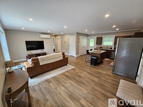 A spacious living room with a brown sofa and a television on the wall.