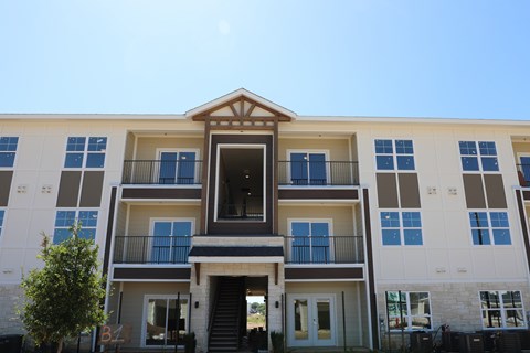 A modern apartment building with a central entrance and balconies on each floor.