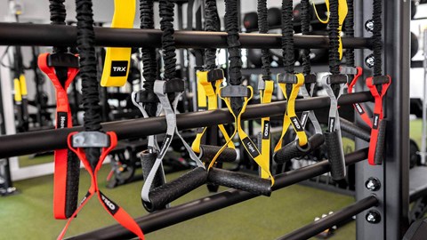 A gym with TRX suspension straps hanging from the ceiling.