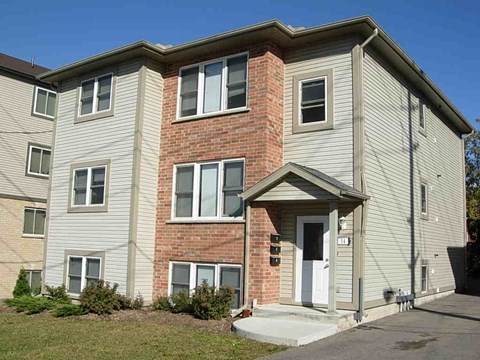 A two-story apartment building with a brick facade and a white door.