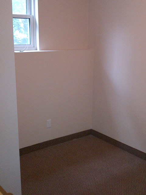 A room with a window and carpeted floor.
