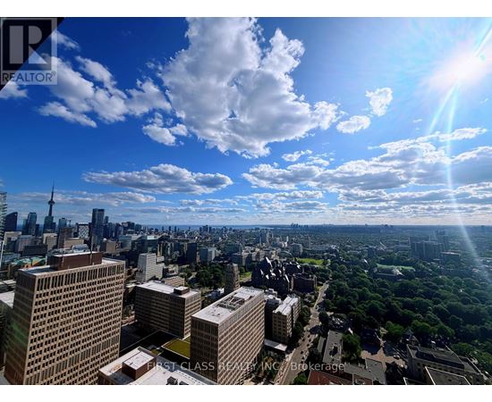 A cityscape with buildings and trees under a blue sky with clouds.