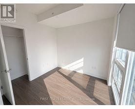 A room with a wooden floor and white walls, with a door on the left and a window on the right.