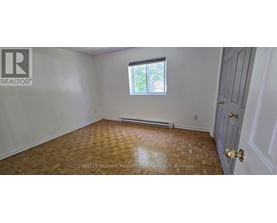 A room with a wooden floor and a window with a view of trees.