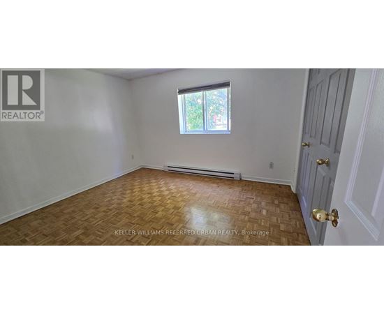 A room with a wooden floor and a window with a view of trees.