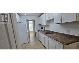 A kitchen with white cabinets and a granite countertop.