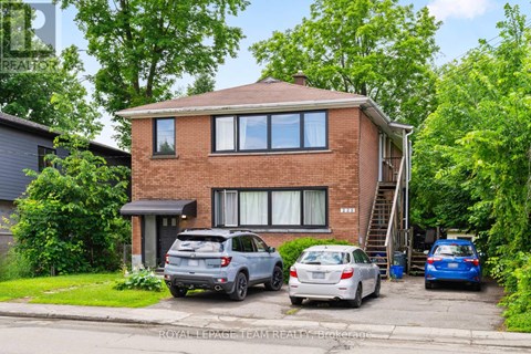 A two-story brick house with a car parked in front.