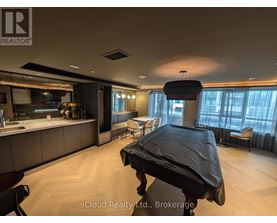 A modern bedroom with a large bed and a kitchen area in the background.