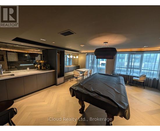 A modern bedroom with a large bed and a kitchen area in the background.