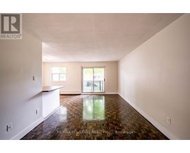 A spacious room with wood flooring and a sliding glass door.