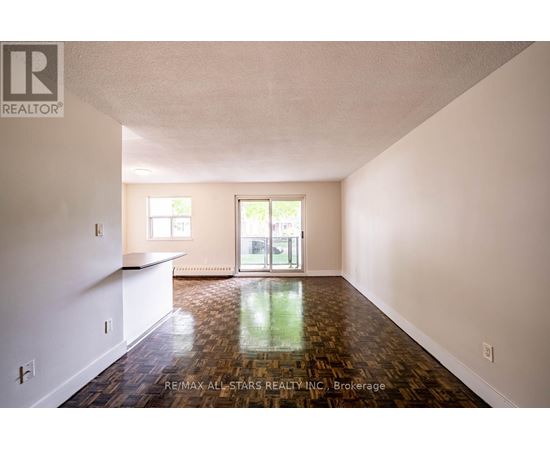 A spacious room with wood flooring and a sliding glass door.