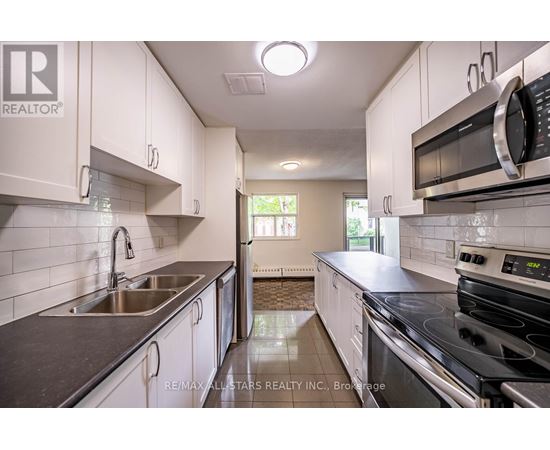 A kitchen with white cabinets and black countertops.