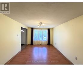 A spacious room with wooden floors and a large window with curtains.