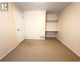 A bedroom with a door, a shelf, and a carpeted floor.