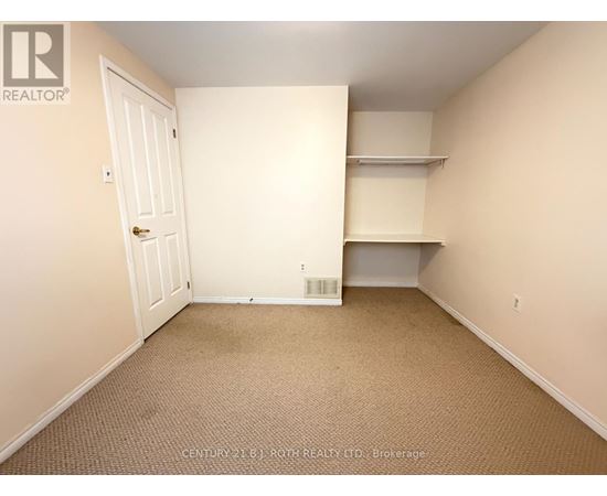 A bedroom with a door, a shelf, and a carpeted floor.