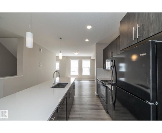 A modern kitchen with a black refrigerator and wooden cabinets.
