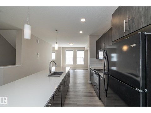 A modern kitchen with a black refrigerator and wooden cabinets.