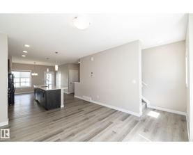 A spacious living room with a dark wood floor and white walls.