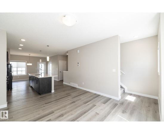 A spacious living room with a dark wood floor and white walls.