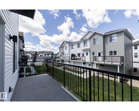 A balcony of a building with a black railing and a grey floor.