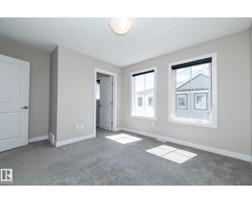 A spacious room with a carpeted floor and three windows.