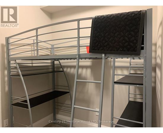 A metal bunk bed with a black mattress on top and a grey mattress on the bottom.