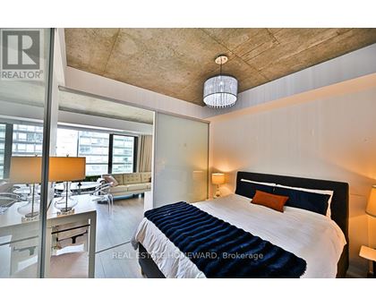 A bedroom with a large bed and a window overlooking a city.