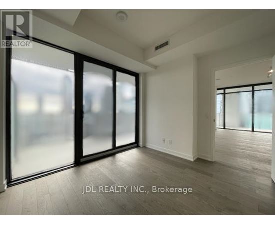 A spacious room with a sliding glass door and wooden flooring.