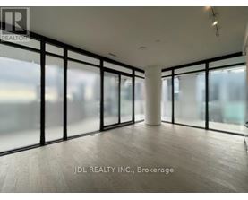 A spacious room with large windows and wooden flooring.