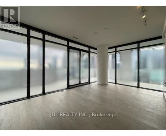 A spacious room with large windows and wooden flooring.