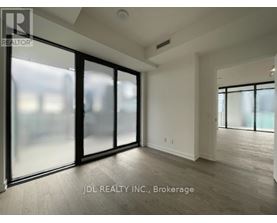 A spacious room with a sliding glass door and wooden flooring.