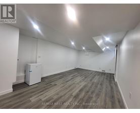 A spacious room with a wood floor and white walls.