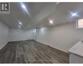 A room with wooden flooring and white walls, with a window on the right side.
