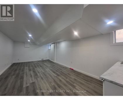 A room with wooden flooring and white walls, with a window on the right side.