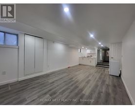 A spacious room with wooden flooring and white walls, with a door on the right side.