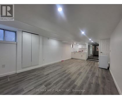 A spacious room with wooden flooring and white walls, with a door on the right side.